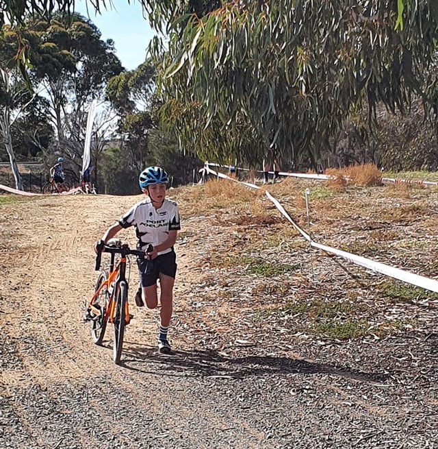 A girl runs with her bike towards the finish line